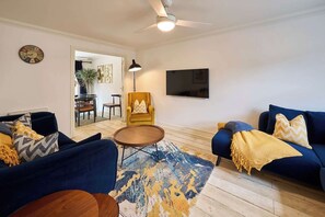 A living room with a sofa, armchair, coffee table, and a flat-screen TV mounted on the wall. - #112 Blueberry cottage Cornwall 4 bed 4 bathroom (Cornwall)