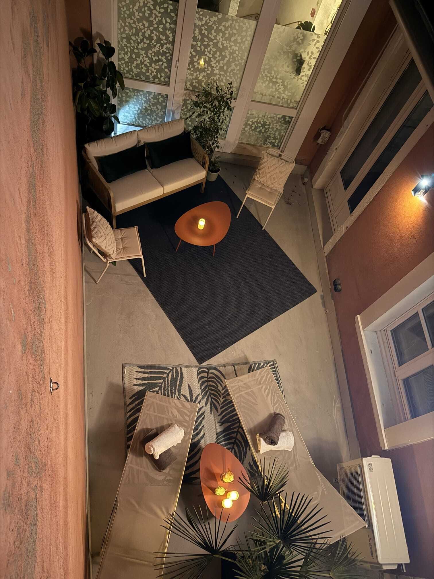 Una terrazza sul tetto con un divano, due tavoli e piante in vaso.