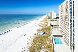 Ein Strandhotel mit Pool, Strandliegen und freiem Blick auf das Meer.