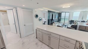 A modern kitchen with a marble countertop, a dining area with a round table, and a view of the sea through large windows. - Sundestin 1014 - Beautiful remodeled 1 BR sleeps 4 (Destin)