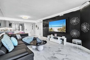 Ein modernes Wohnzimmer mit Schwarz-Weiß-Farbschema, einem großen Flachbildfernseher und dekorativen Wandbildern.