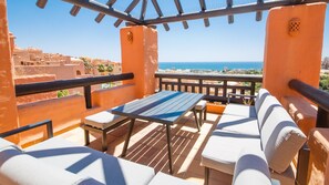 A terrace with a table and chairs, overlooking a coastal view. - Coto Real apartment Zira 321 (Manilva)
