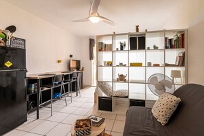 Un espace de vie compact comprenant un coin cuisine, un coin repas et une bibliothèque.