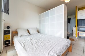 A bedroom with a bed, a wardrobe, a bedside table, and a lamp. - Le Cocon de Moriani - Climatisé et plage à 100 m (San-Nicolao)