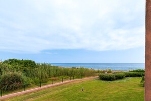 Eine Küstenlandschaft mit einem gepflasterten Weg, viel Grün und Blick auf das Meer.