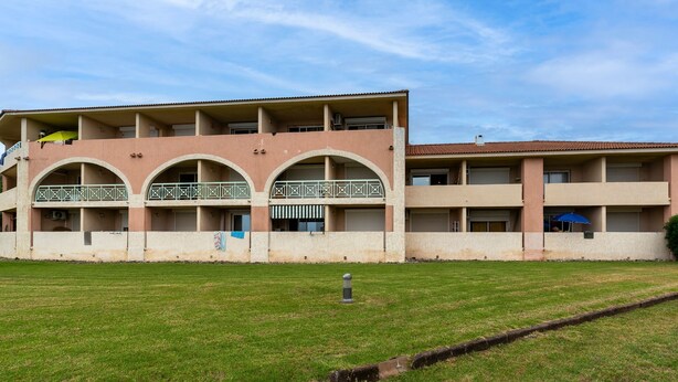 Un edificio a più piani con tetto piatto, un cortile lastricato d'erba e un canale di scolo.