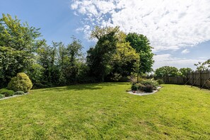 A well-maintained backyard with a lawn, a variety of trees, and a wooden fence. - Ecurie des Fieffes - Maison au calme en campagne (Ozeville)