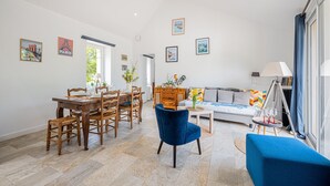Un amplio espacio de sala con una mesa de comedor, sillas, un sofá y un sillón azul.