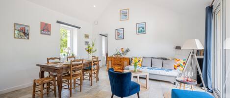 A spacious living area with a dining table, chairs, a sofa, and a blue armchair.