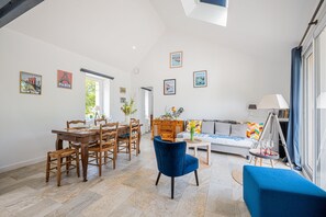 A spacious living area with a dining table, chairs, a sofa, and a blue armchair. - Ecurie des Fieffes - Maison au calme en campagne (Ozeville)