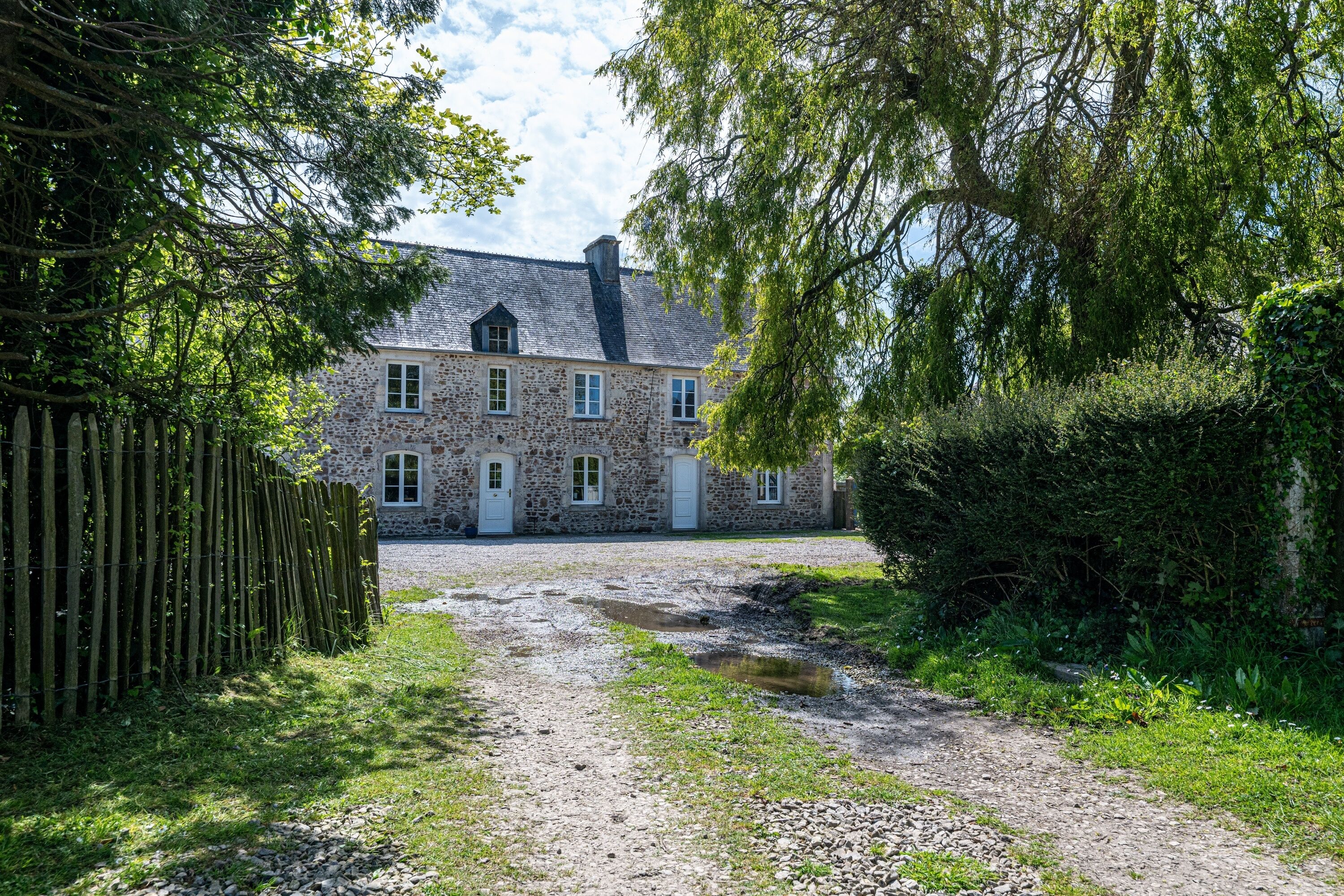 A stone building with a gravel driveway leading to a white door.