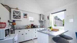Una cocina moderna con armarios blancos, estufa integrada y un amplio ventanal con vistas al exterior.