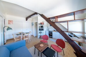 A compact living space with a dining area, a sofa, a coffee table, and a kitchen with a microwave and stove.