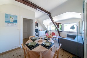 A dining area with a table set for four, a kitchen in the background, and a living area with a sofa.