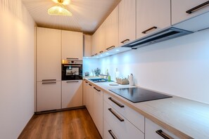 A modern kitchen with white cabinetry, a black countertop, and a built-in oven. - La Yaute - Bel appt rénové à 2 pas du lac Léman (Evian-les-Bains)