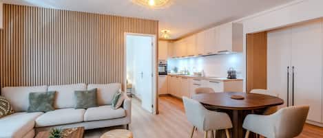 Un salon moderne comprenant un canapé, une table basse et un coin repas avec une table et des chaises en bois.