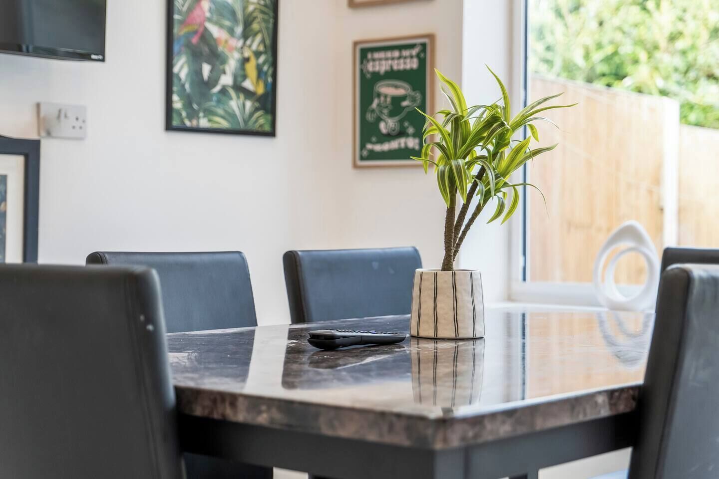 A dining area with a table, chairs, and a potted plant.