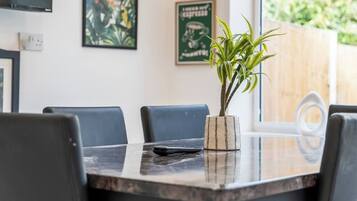A dining area with a table, chairs, and a potted plant.