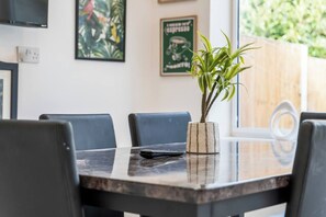 A dining area with a table, chairs, and a potted plant. - #126 Cosy 5 mins to Coventry Cathedral | sleeps 7 (West Midlands)