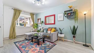 A living room with a sofa, coffee table, patterned rug, and a floor lamp.