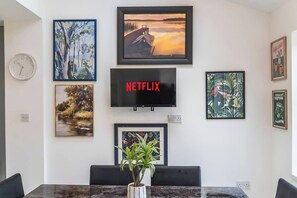 Une pièce avec un téléviseur fixé au mur, une horloge et divers tableaux encadrés.