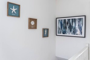 A hallway with three framed artworks on the wall, a staircase with white railings, and a plain white wall. - #126 Cosy 5 mins to Coventry Cathedral | sleeps 7 (West Midlands)