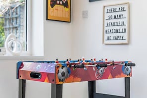 A foosball table with a colorful design, a motivational quote on the wall, and a window with a view of a building. - #126 Cosy 5 mins to Coventry Cathedral | sleeps 7 (West Midlands)