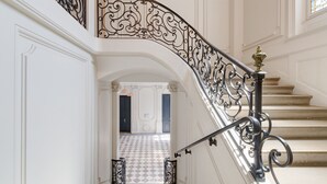 A grand staircase with ornate black metal railings and a checkered floor pattern. - L'Escale Rémoise - À 600 m de la Porte de Mars (Reims)