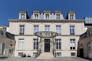 A large, classical building with a symmetrical facade, multiple windows, and a central entrance with a decorative canopy. - L'Escale Rémoise - À 600 m de la Porte de Mars (Reims)