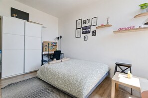 Ein Schlafzimmer mit einem Bett, einem Schreibtisch, einem Stuhl, einem Kleiderschrank und einem kleinen Tisch.