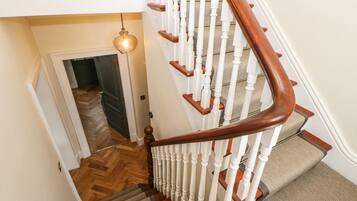Una escalera de madera con balaustres blancos y un rellano alfombrado.