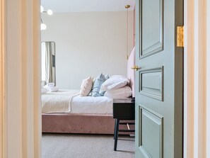Un dormitorio con cama, mesita de noche y una puerta.