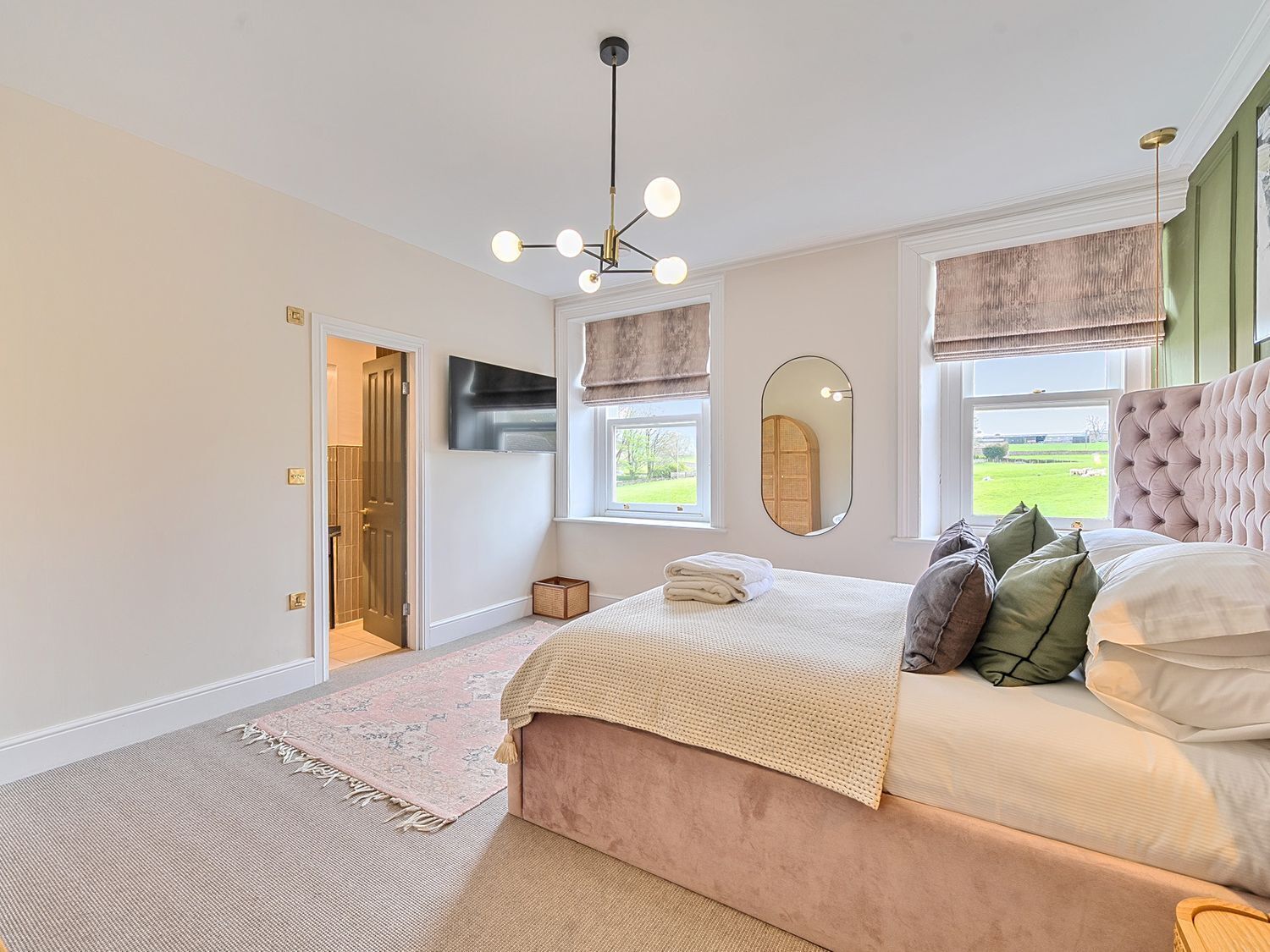 A bedroom with a bed, a mirror, a window, and a door.