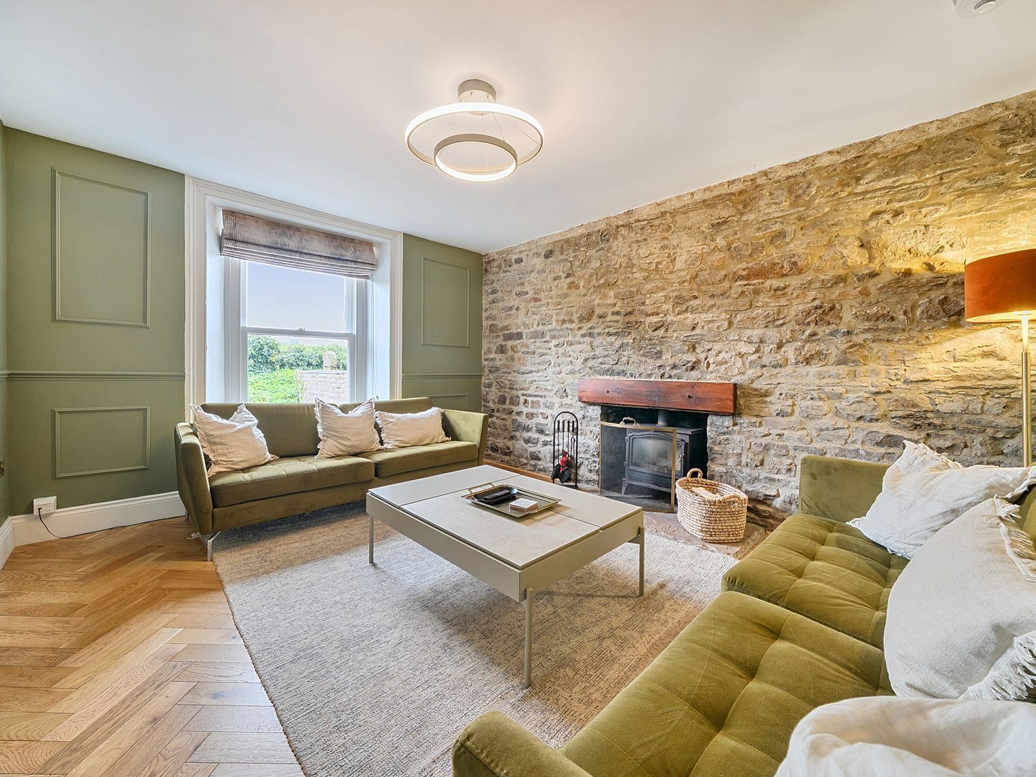 Un salon chaleureux avec un mur en pierre, une cheminée, un canapé et une table basse.