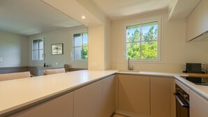 Una cucina moderna con un'isola grande, una finestra vista su del verde e un forno a incasso.