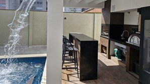 Un patio exterior con piscina, barra y zona de estar.