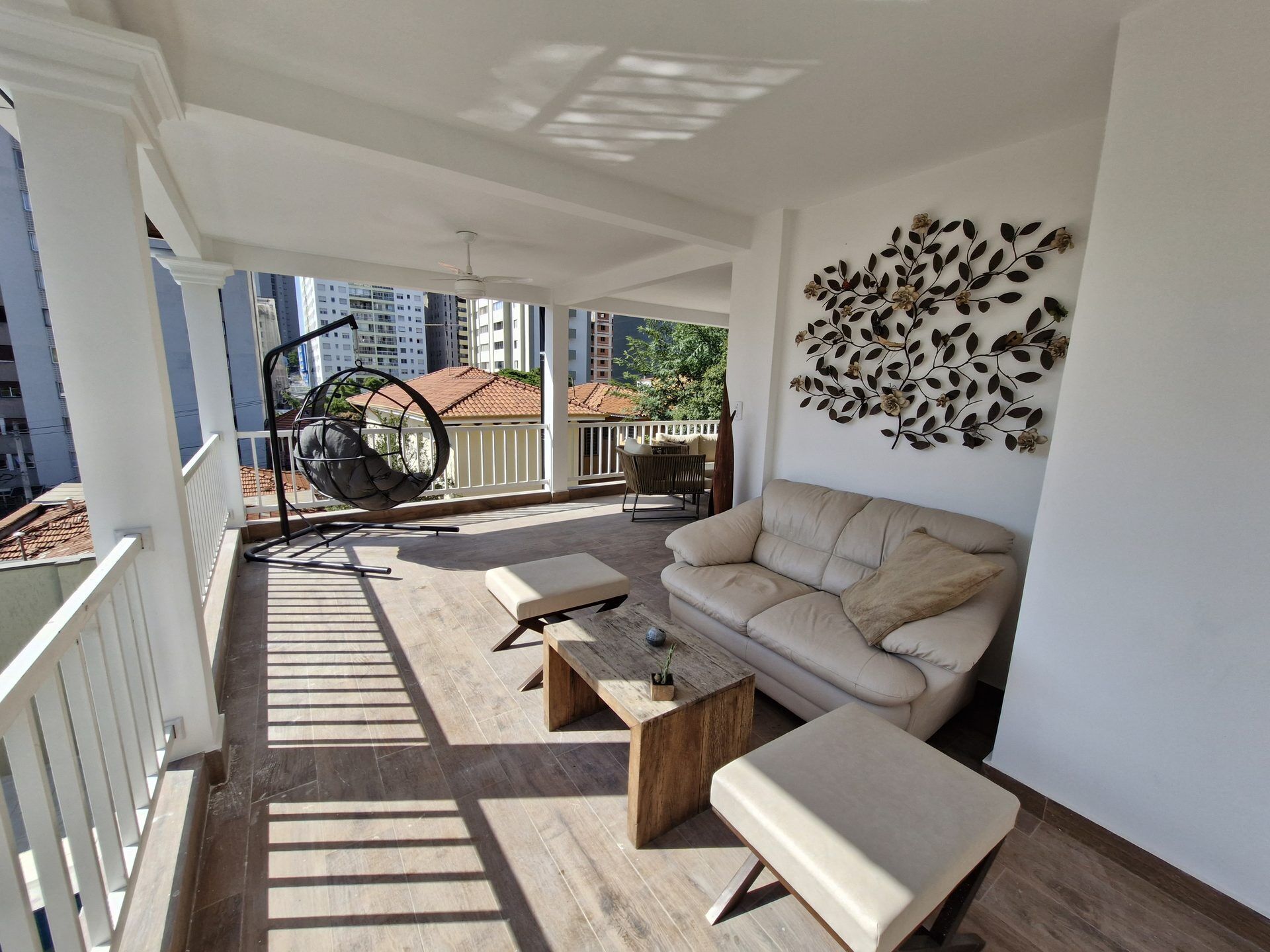 A balcony with a hanging chair, a sofa, and a coffee table.