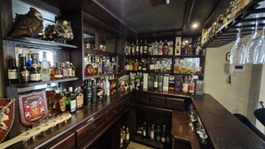 Zona de bar con estantes llenos de botellas de licores y vasos.