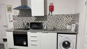 A compact kitchen with a microwave, oven, and washing machine. - #127 Modern City Suite | Digbeth Creative Quarter (West Midlands)
