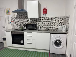 A compact kitchen with a microwave, oven, and washing machine. - #127 Modern City Suite | Digbeth Creative Quarter (West Midlands)
