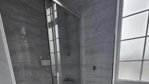 A bathroom with a glass shower enclosure, a toilet, and a window. - #127 Modern City Suite | Digbeth Creative Quarter (West Midlands)