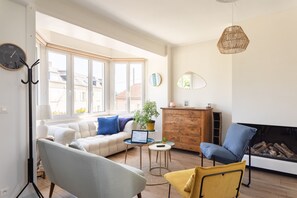 Ein modernes Wohnzimmer mit einer Couch, Sesseln, einem Couchtisch und einem Kamin.