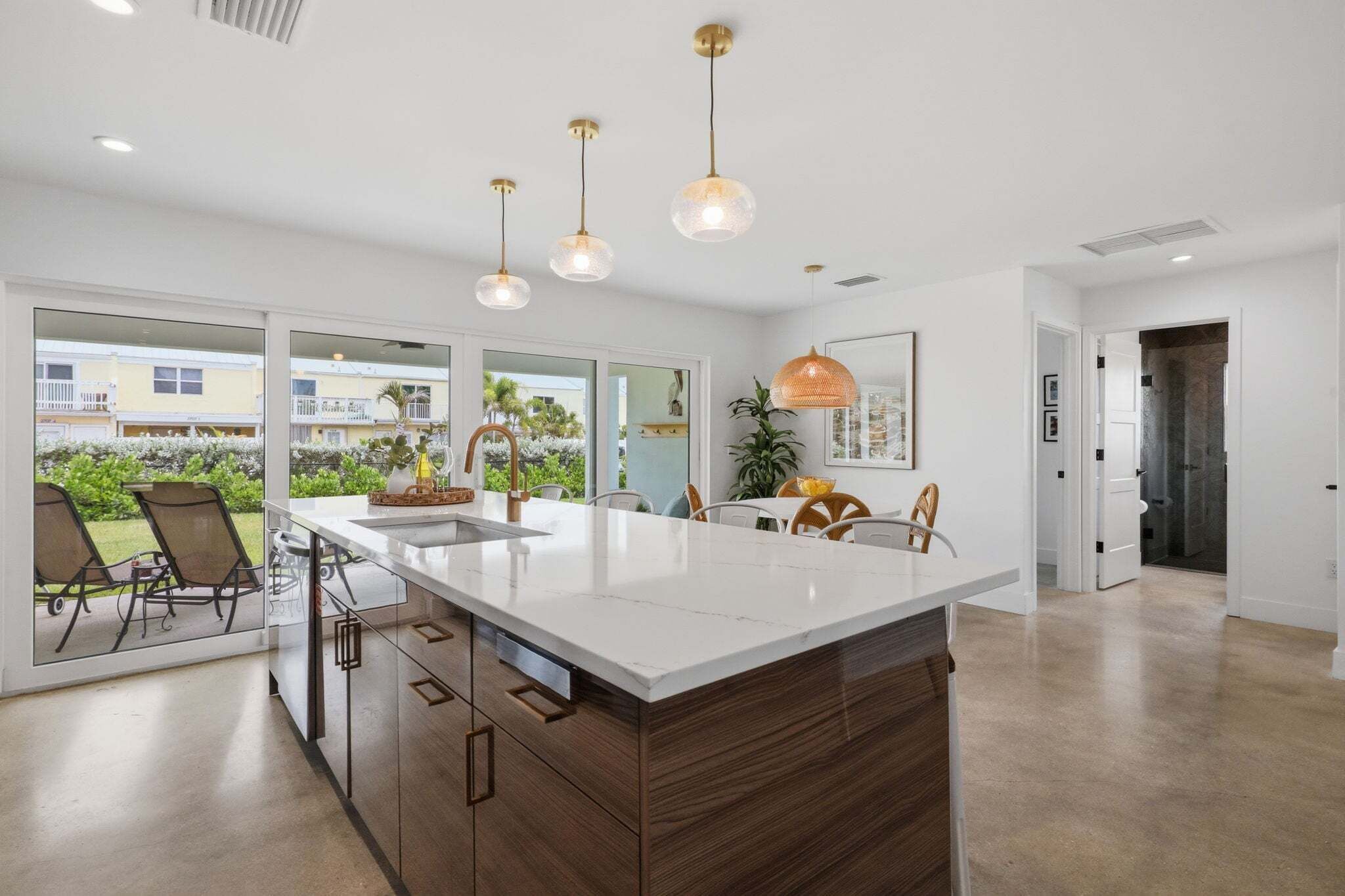 A modern kitchen with a large island, pendant lighting, and a view of the outdoors.