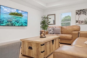 Ein Wohnzimmer mit Fernseher, Couch, Holz-Couchtisch und einer Pflanze.