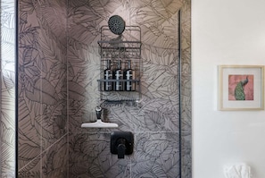 Ein Badezimmer mit Duschbereich, Handtuchhalter und einem gerahmten Bild an der Wand.