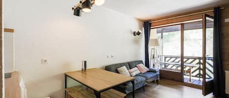 Habitación acogedora con una mesa de madera, un sofá y un banco. Se ve una ventana con vistas al exterior.