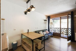 A cozy room with a wooden table, a sofa, and a bench. There is a window with a view of the outdoors. - Chez Joséphine - Station de ski accessible à pied (Gresse-en-Vercors)