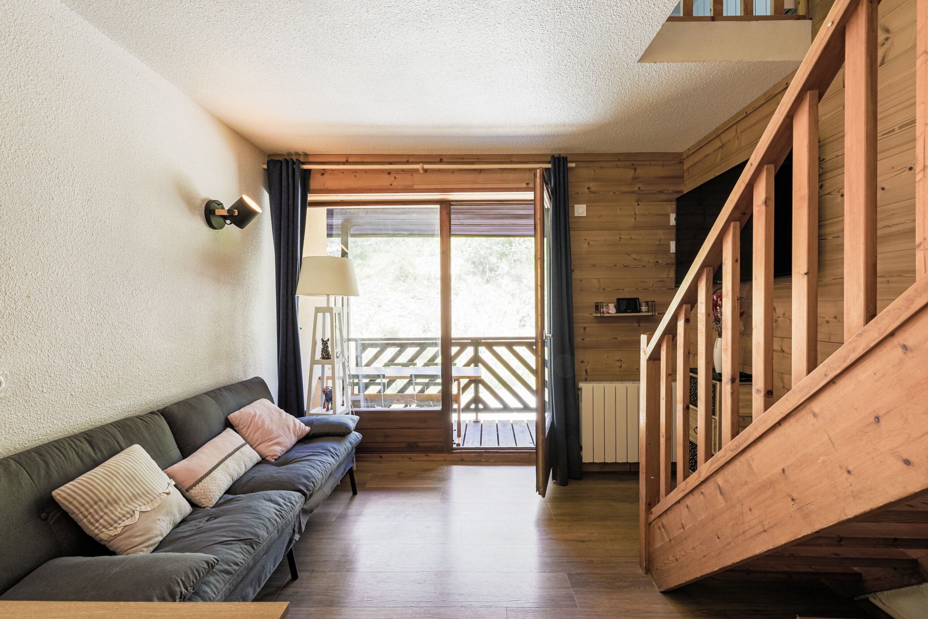 A wooden interior with a sofa, a lamp, and a staircase.