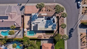 A residential area with a house featuring a swimming pool, solar panels, and a well-maintained garden with palm trees. - Palm Springs Retreat-Come and relax. (Palm Springs)