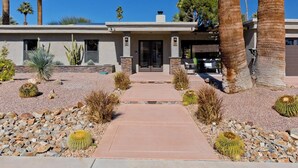 A modern house with a paved driveway, surrounded by desert plants and palm trees. - Palm Springs Retreat-Come and relax. (Palm Springs)